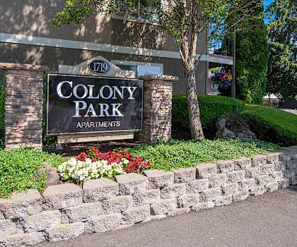 a sign for colony park apartments in front of a stone wall