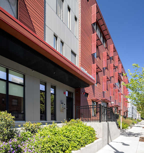 an apartment building on a city street with people walking at The Anne M. Lynch Homes at Old Colony, Massachusetts