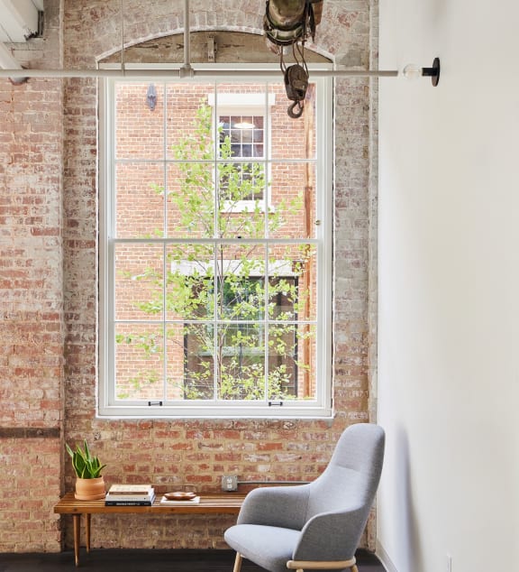 a chair and a window in a room with a brick wall at The Mill at Prattville, Alabama