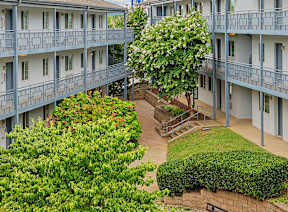 A view of a courtyard with a building in the background and a golden dome on top of a tower.