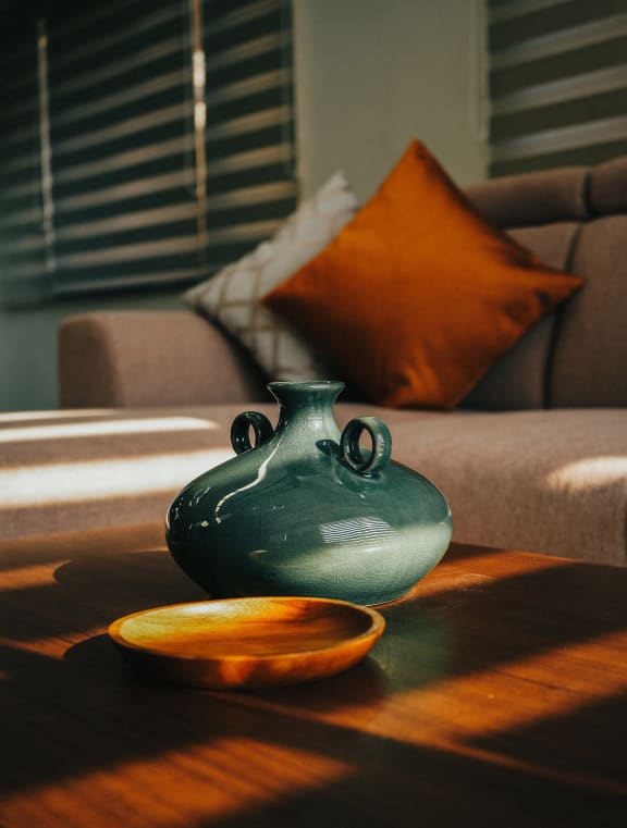 a vase on a table with a couch in the background