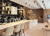 Thumbnail 8 of 15 - A bar with a white counter and brown chairs.