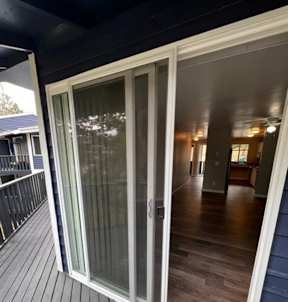 A glass door with a white frame is open, revealing a wooden floor and interior space.