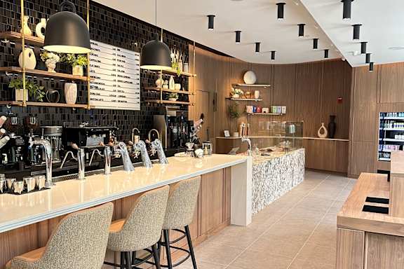 A bar with a white counter and brown chairs.