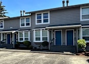 Thumbnail 8 of 8 - A grey house with a dark blue door and windows.