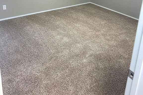 A room with a carpeted floor and a window with blinds.