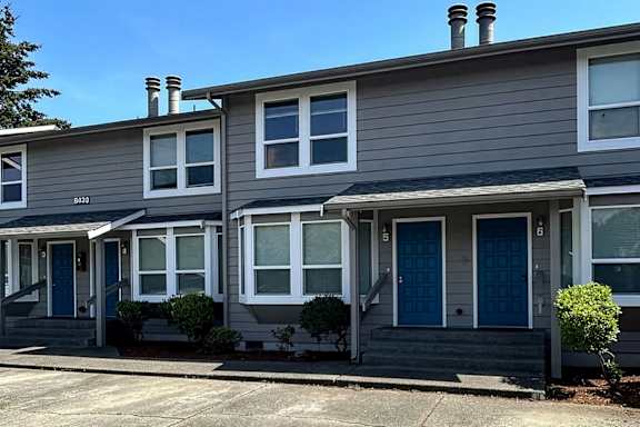 A grey house with a dark blue door and windows.