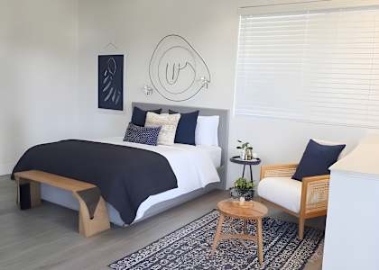 A bedroom with a bed, a bench, and a rug.