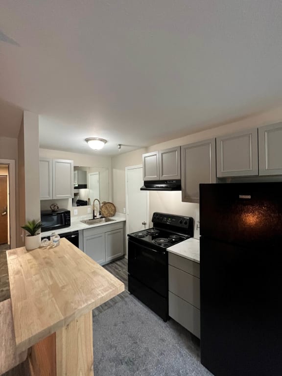 a kitchen with white cabinets and black appliancesat The Lodge Apartments, Tulsa, 74129