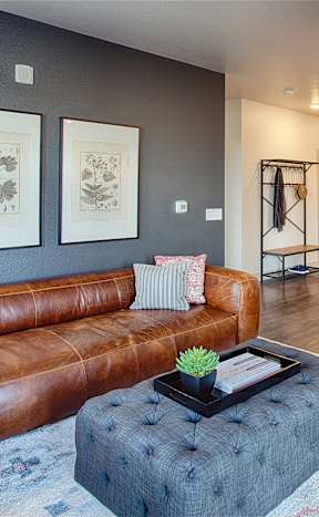 a living room with a brown leather couch and a blue ottoman