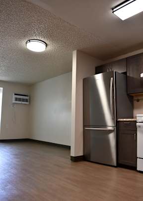 A kitchen with a stainless steel refrigerator and a white wall.