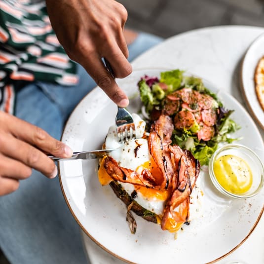 a person cutting into a plate of food with a knife and fork