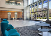 Thumbnail 2 of 18 - A modern interior with blue chairs and a glass ceiling.