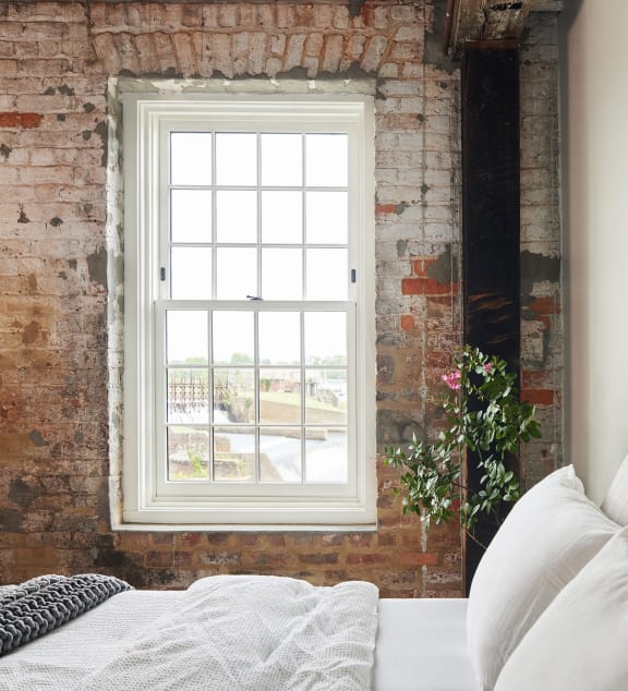 a bedroom with a brick wall and a window  at The Mill at Prattville, Alabama