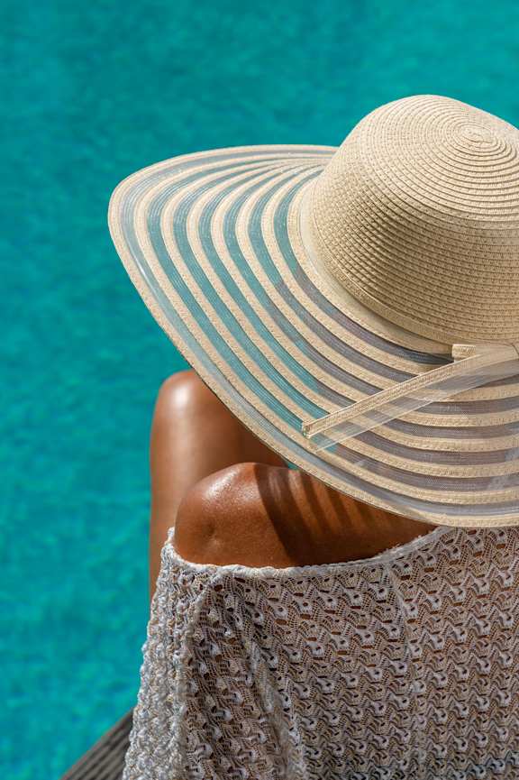Woman wearing hat and sitting by the pool at Amara Luxury Apartments, Sacramento, California