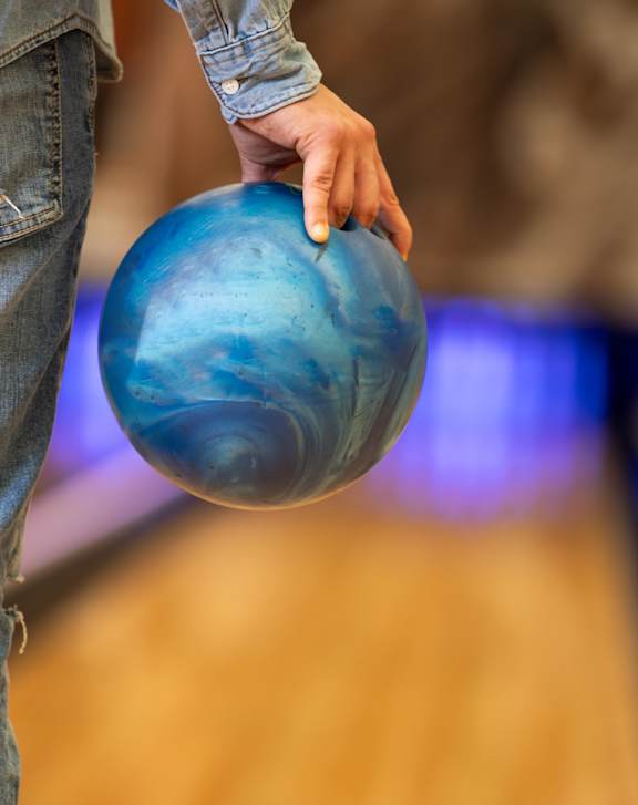 A person is holding a blue bowling ball.