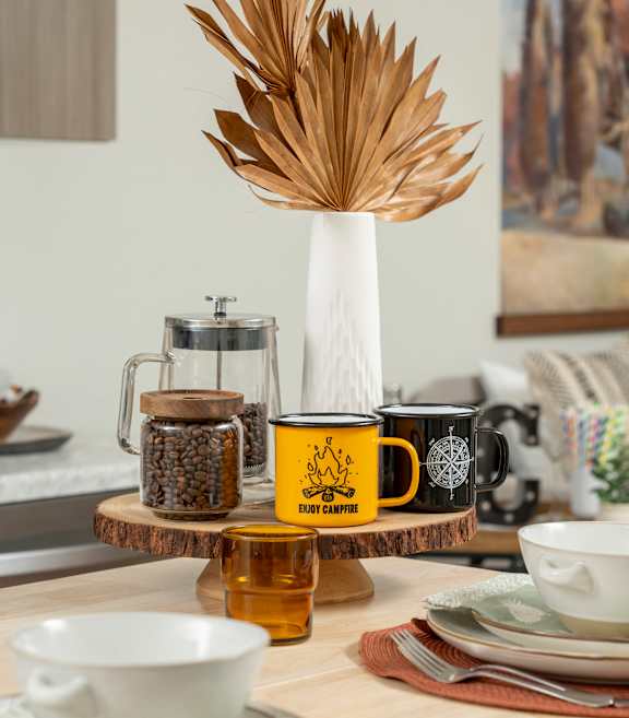 A kitchen counter with a green kettle, a wooden cutting board, and a sink.
