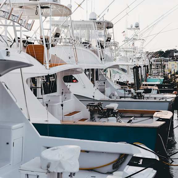 A row of boats are docked at a marina.