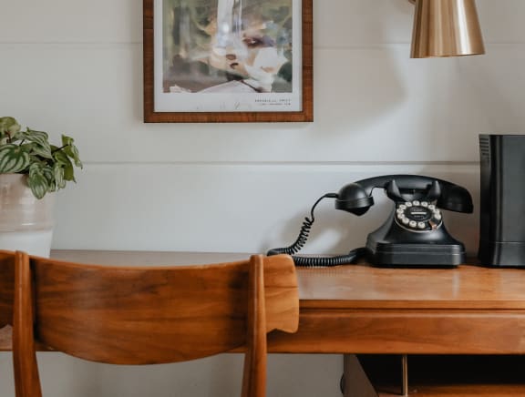 a desk with a phone and a chair in a room