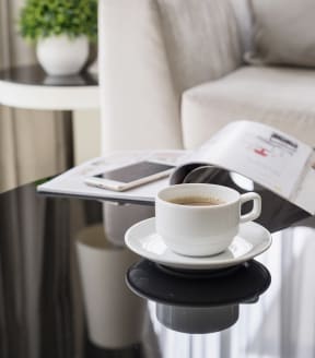 Cup of Coffee On Coffee Table In Living Room With Phone & Magazine
