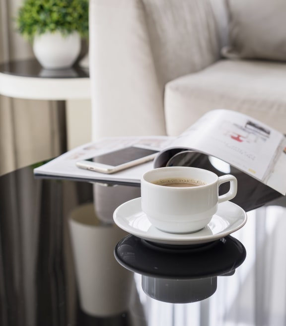 Cup of Coffee On Coffee Table In Living Room With Phone & Magazine
