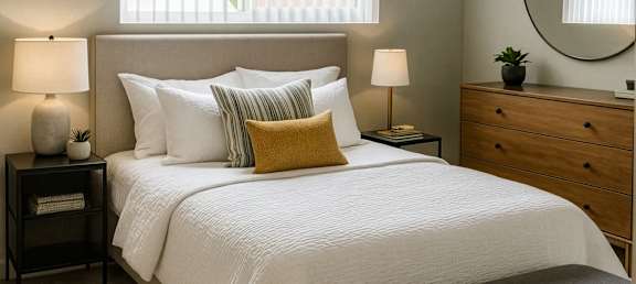 A bedroom with a bed, nightstands, and a bench.
