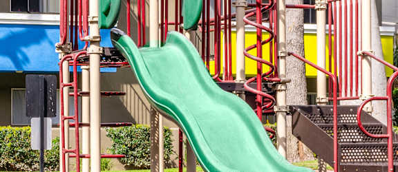 a playground with a green slide in front of a building
