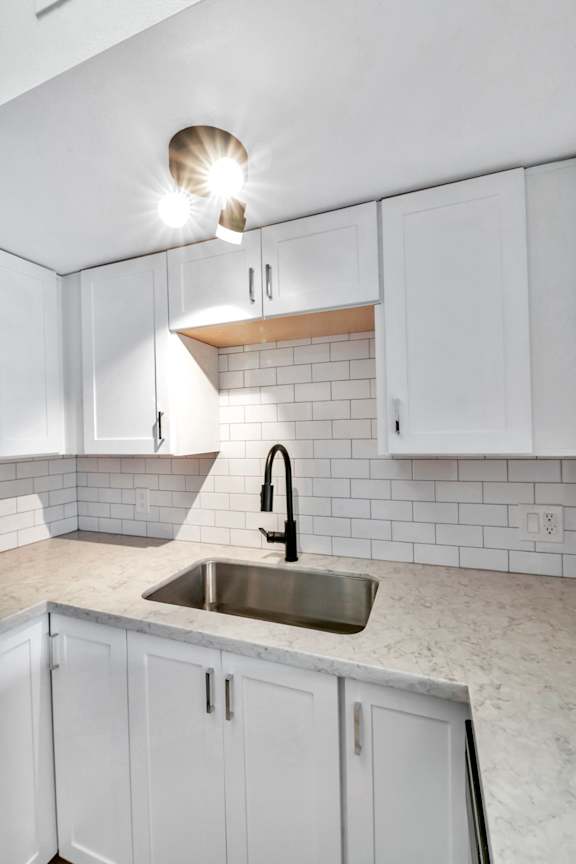 A kitchen with white cabinets and a sink.