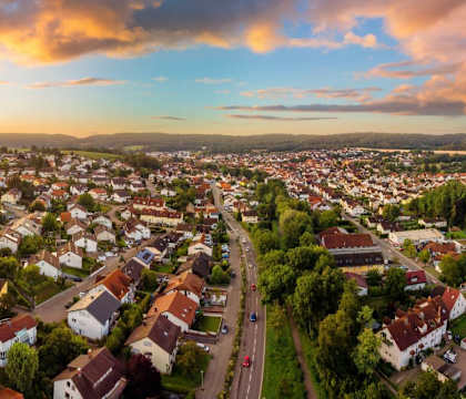 a sunset over a suburb of a city with houses and trees