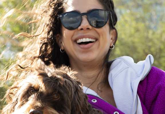 A woman in a purple jacket is holding a dog.