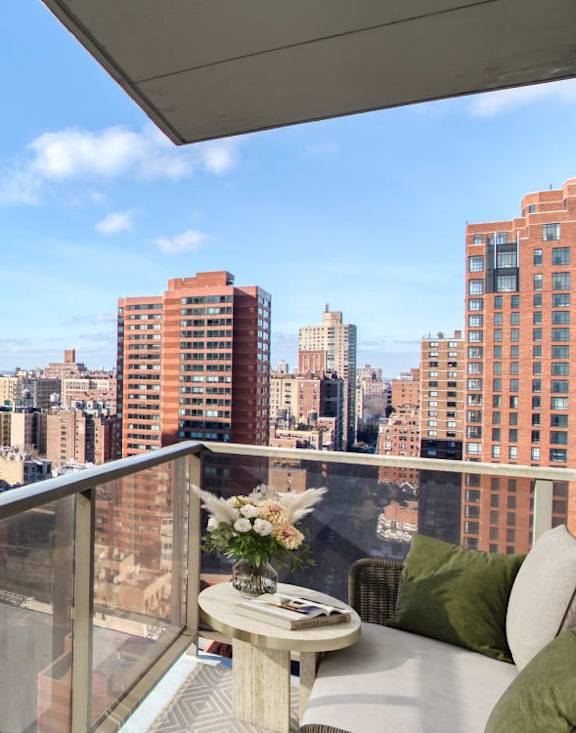 A balcony with a table and chairs overlooks a city skyline.at 301E94, New York, NY