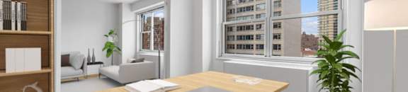 A laptop is on a wooden desk in a room with a large window at The Caldwell Apartments, New York, 10028