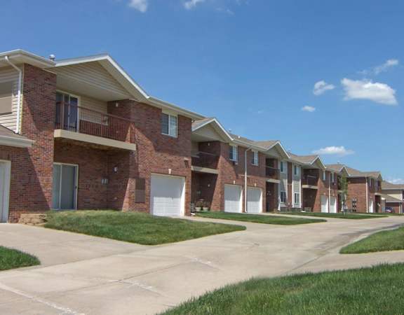 Exterior area of town homes with green yards and garages.