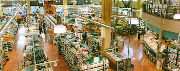 a large supermarket filled with lots of produce and people shopping