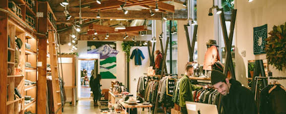 a man working on a laptop in a clothing shop