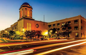 A long exposure shot of a street with a clock tower at dusk.