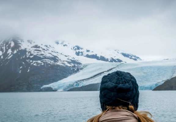 a woman looking out over a body of water with a glacier at Woodridge Apartments, Kenai