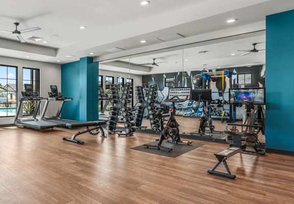 A gym with a variety of equipment including treadmills, weights, and exercise machines.