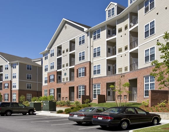 a parking lot with cars in front of an apartment building