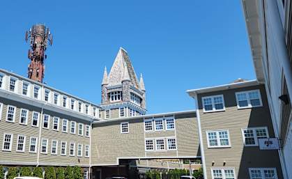 A building with a tower in the background and a building in the foreground.