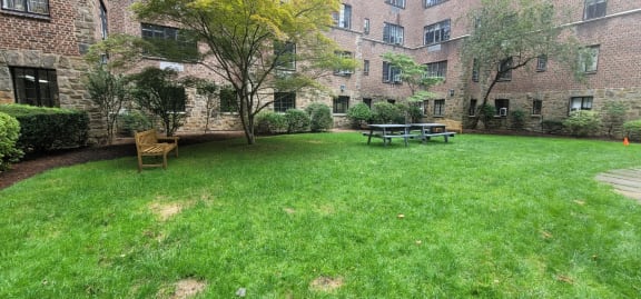a backyard with a grassy area and a picnic table in front of a brick building