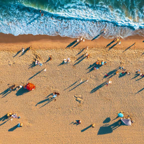 a aerial view of a beach with people walking on the sand and the ocean in the background