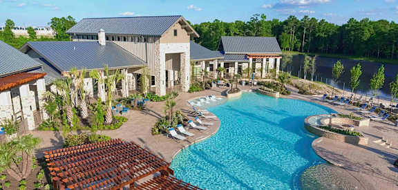 an aerial view of a large swimming pool with patio furniture
