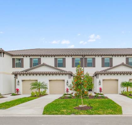 a large white house with two garage doors and a driveway at Fiore Townhomes, Venice, FL, 34275