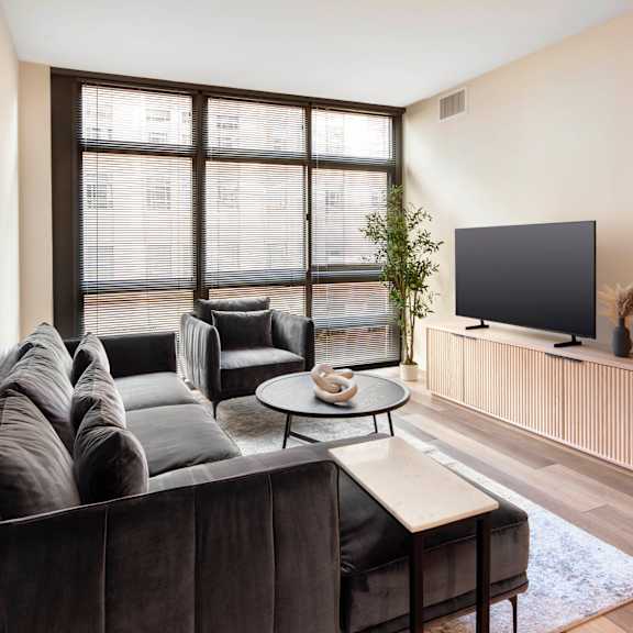 A grey couch with a white coffee table in front of a large window.