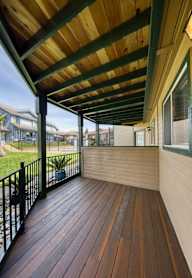 A wooden deck with a green railing and a roof.