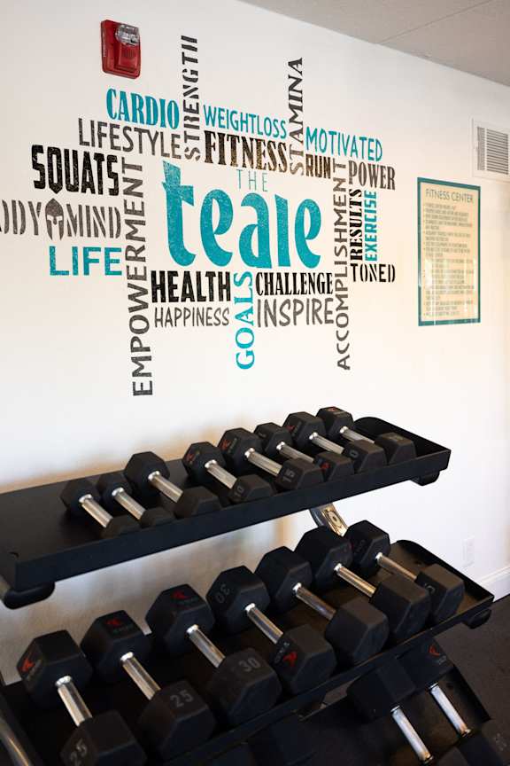 a wall with weights and words on the wall above a row of dumbbells at The Teale, Kissimmee, FL, 34746