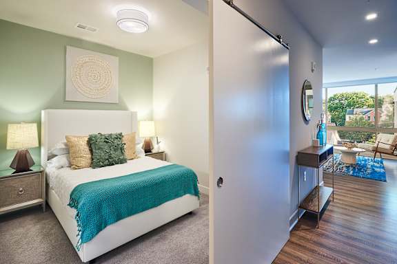 A bedroom with a bed, nightstand, and a mirror on the wall.