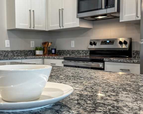 A white bowl sits on a plate on a granite countertop.
