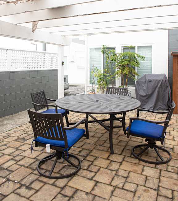 A table with two chairs and a plant on a patio.